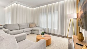 A modern living room with a sectional sofa, a round coffee table, and a flat-screen TV. - Mickey & Mario Luxury Retreat, private pool (Kissimmee)