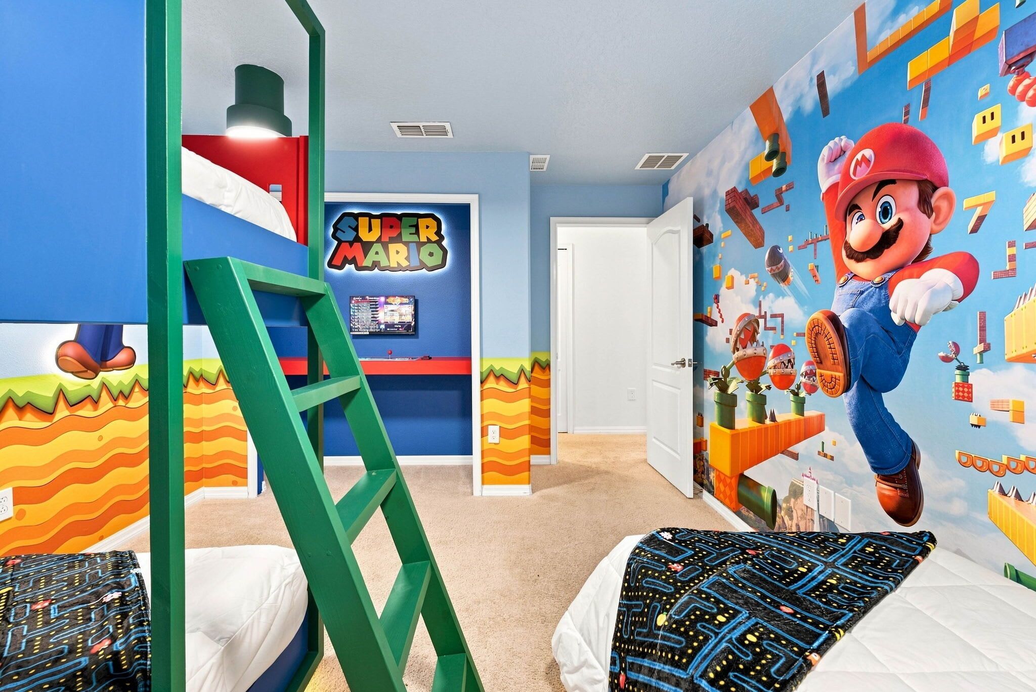 Habitación infantil con un mural temático de Mario, una escalera y una cama con colcha estampada.
