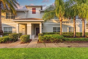 A two-story house with a covered porch, palm trees, and well-maintained hedges. - Mickey & Mario Luxury Retreat, private pool (Kissimmee)