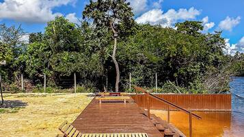 A wooden deck with benches and a railing, leading to a body of water.