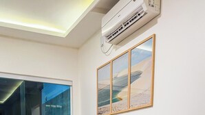 Una sala de estar con un sofá color beige, una mesita de madera y un cuadro en la pared.