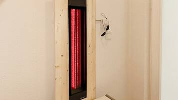 A room with a wooden panel wall, a red curtain, and a small shelf with a pair of glasses.