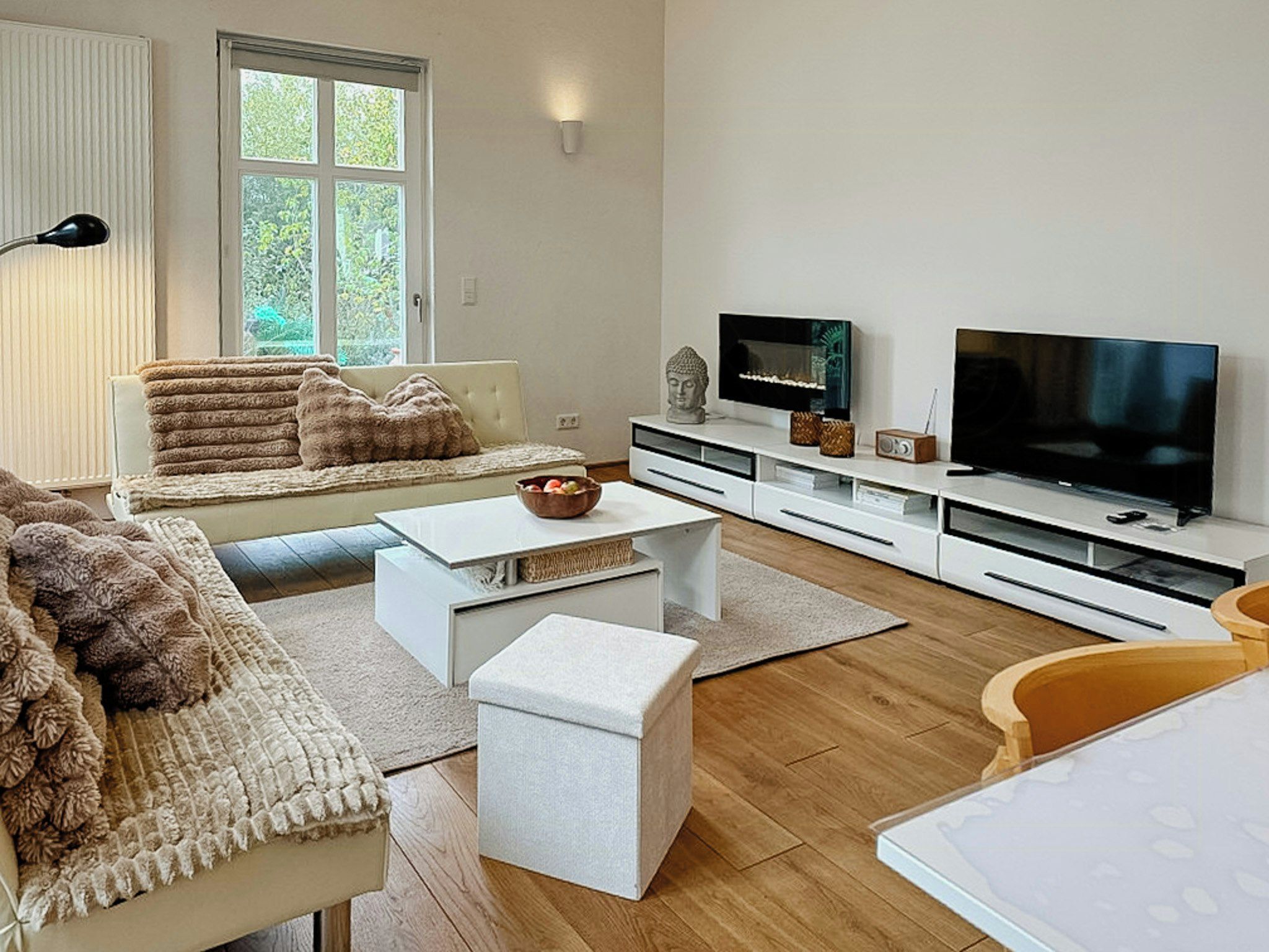 Un salon moderne avec un canapé, une table basse, un téléviseur et un plancher en bois.