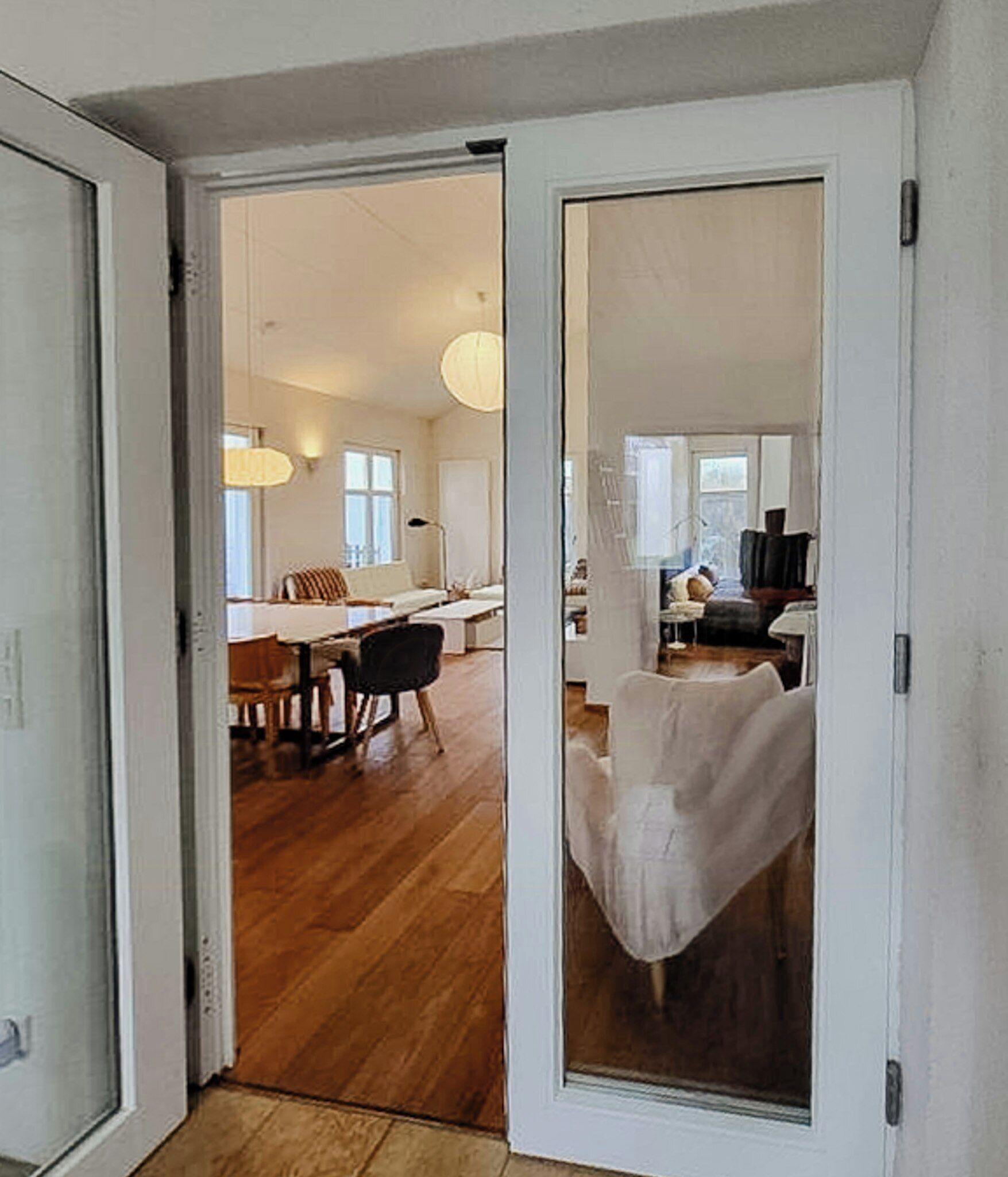 A modern interior with a wooden floor, a dining area with a table and chairs, and a seating area with a sofa and a chair.