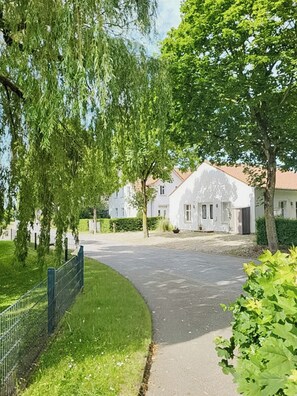 A residential street with houses, a curved driveway, and a fence.