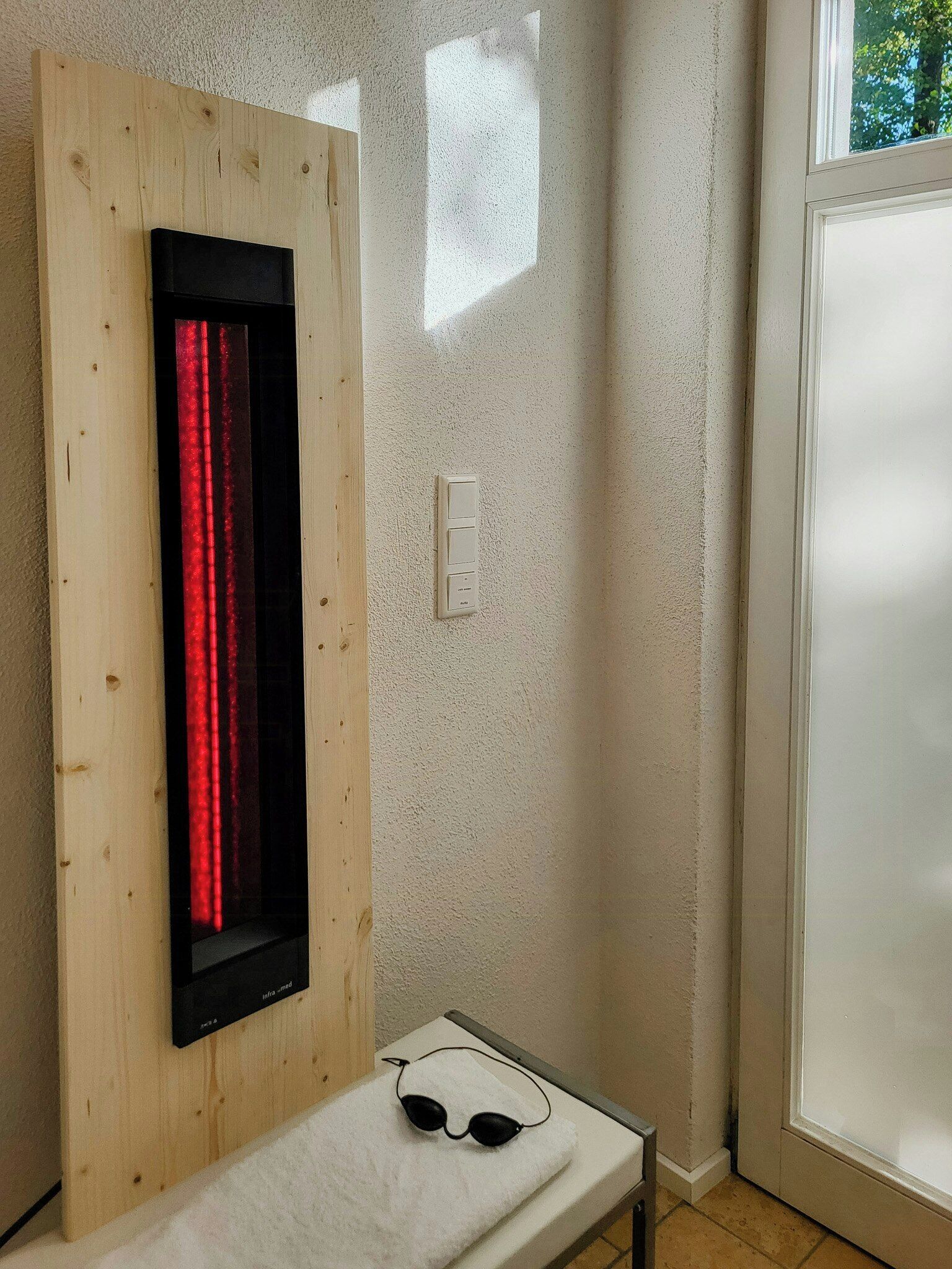 Une salle de bain avec un mur lambrissé, une serviette et une paire de lunettes de soleil posées sur un comptoir.
