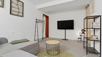 Ein modernes Wohnzimmer mit einer Couch, einem Couchtisch, einem Fernseher und einem Bücherregal.