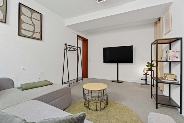 A modern living room with a sofa, a coffee table, a TV, and a bookshelf.