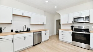 Eine moderne Küche mit weißen Schränken, Edelstahlgeräten und einer Holz Arbeitsplatte.