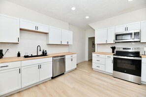 Eine moderne Küche mit weißen Schränken, Edelstahlgeräten und einer Holz Arbeitsplatte.