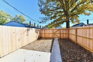 A fenced backyard with a concrete pathway and a tree. - Fenced yard • pets • parking • IMS + downtown (Indianapolis)