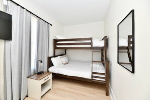 A bunk bed room with a bedside table, a lamp, and a mirror on the wall. - Fenced yard • pets • parking • IMS + downtown (Indianapolis)