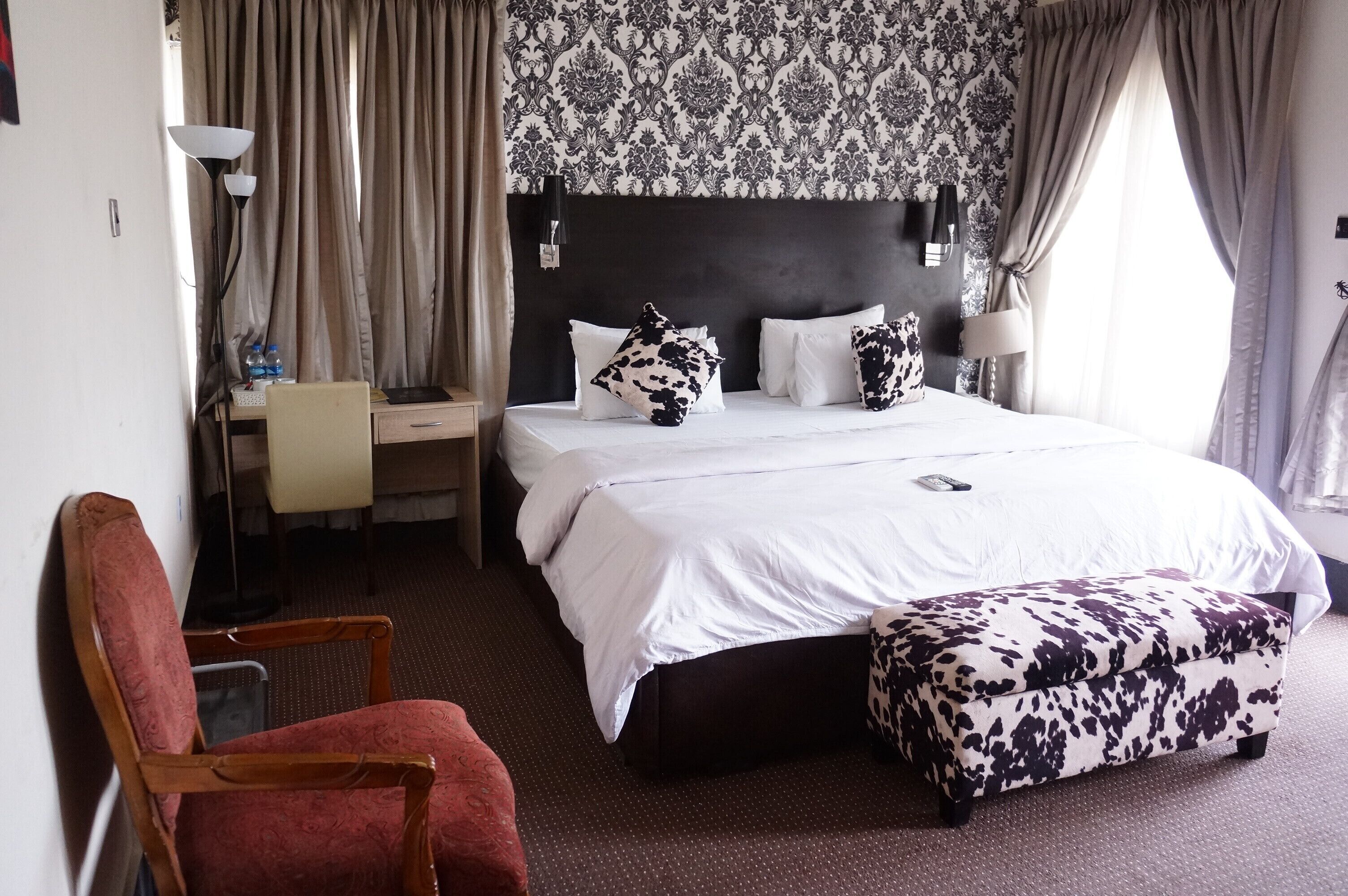 Quarto de hotel com uma cama grande, uma escrivaninha, uma cadeira e um guarda-roupa.