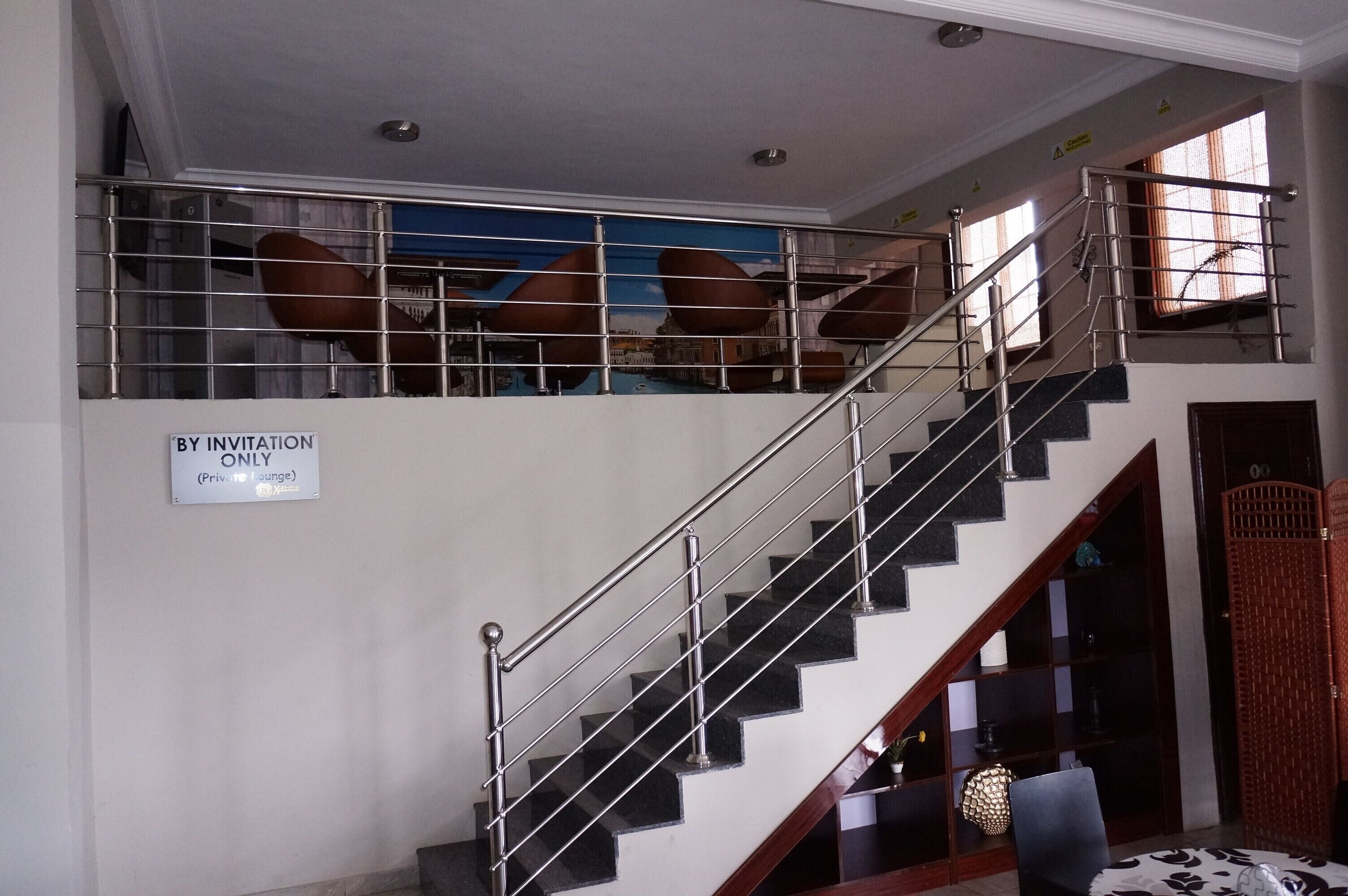 Escadaria com guarda-corpo de metal e placa indicando 'SOMENTE POR CONVITE' para um lounge privativo.