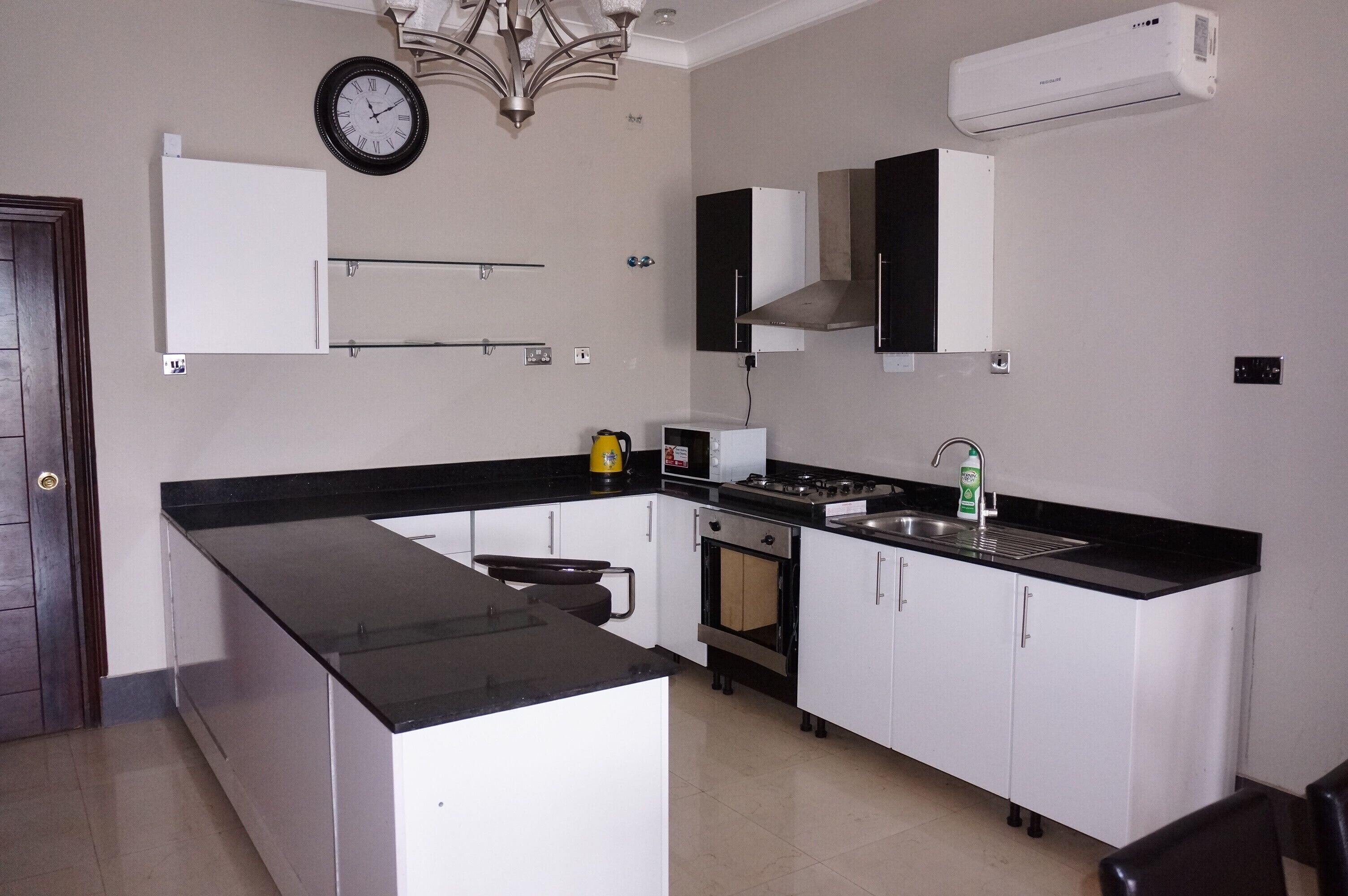 A modern kitchen with a black countertop, white cabinets, a stove, and an oven.