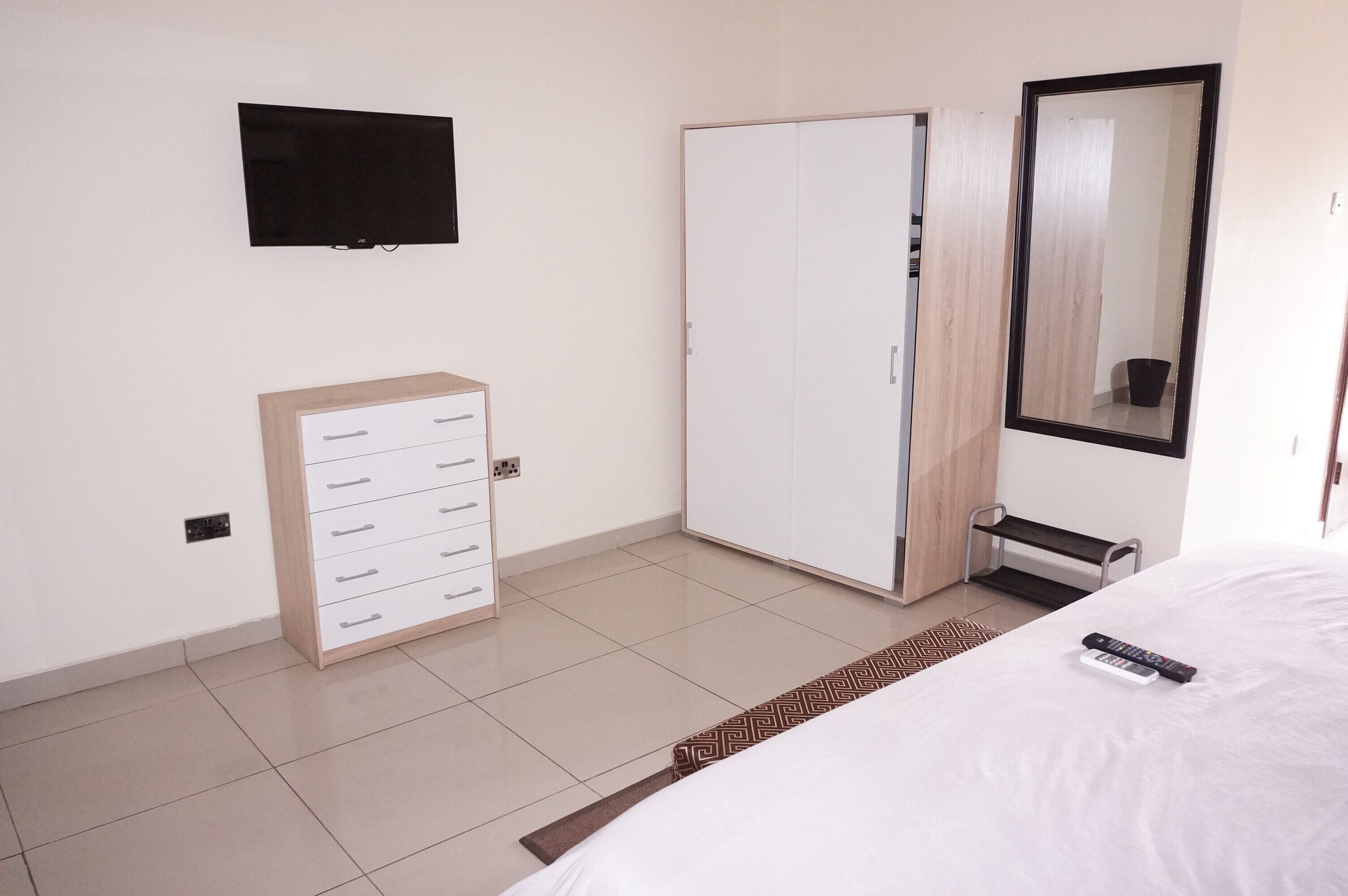 A hotel room with a bed, a wardrobe, a television, and a mirror.