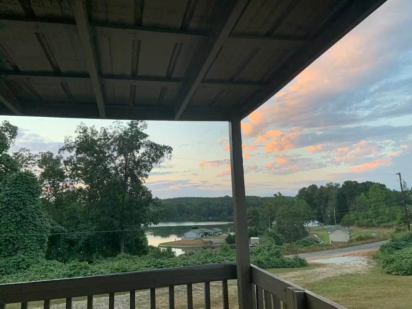 A covered outdoor area with a view of a lake and surrounding greenery.