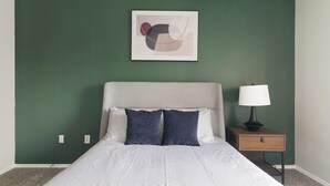 A bedroom with a bed, a nightstand, a lamp, and a wall-mounted abstract artwork. - Landing | Stylish 1BD, Gym, Clubhouse (Houston)