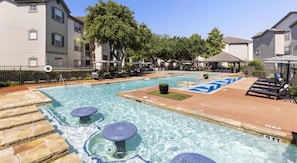 A swimming pool with lounge chairs and a stone deck. - Landing | Stylish 1BD, Gym, Clubhouse (Houston)