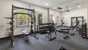 A gym with various exercise equipment, including a squat rack, dumbbells, and benches. - Landing | Stylish 1BD, Gym, Clubhouse (Houston)
