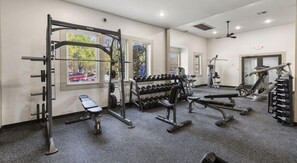 A gym with various exercise equipment, including a squat rack, dumbbells, and benches. - Landing | Stylish 1BD, Gym, Clubhouse (Houston)