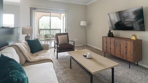 A modern living room with a sofa, armchair, coffee table, and a TV mounted on the wall. - Landing | Modern 1BD, Gym, Clubhouse (Houston)