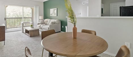 Una sala de estar moderna con una mesa de comedor redonda, sillas de cuero, un sofá y un ventanal grande.