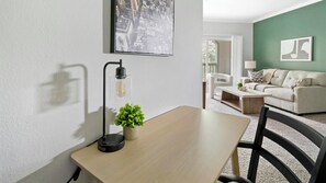 Ein modernes Wohnzimmer mit Holztisch, Stehlampe und grüner Wand.