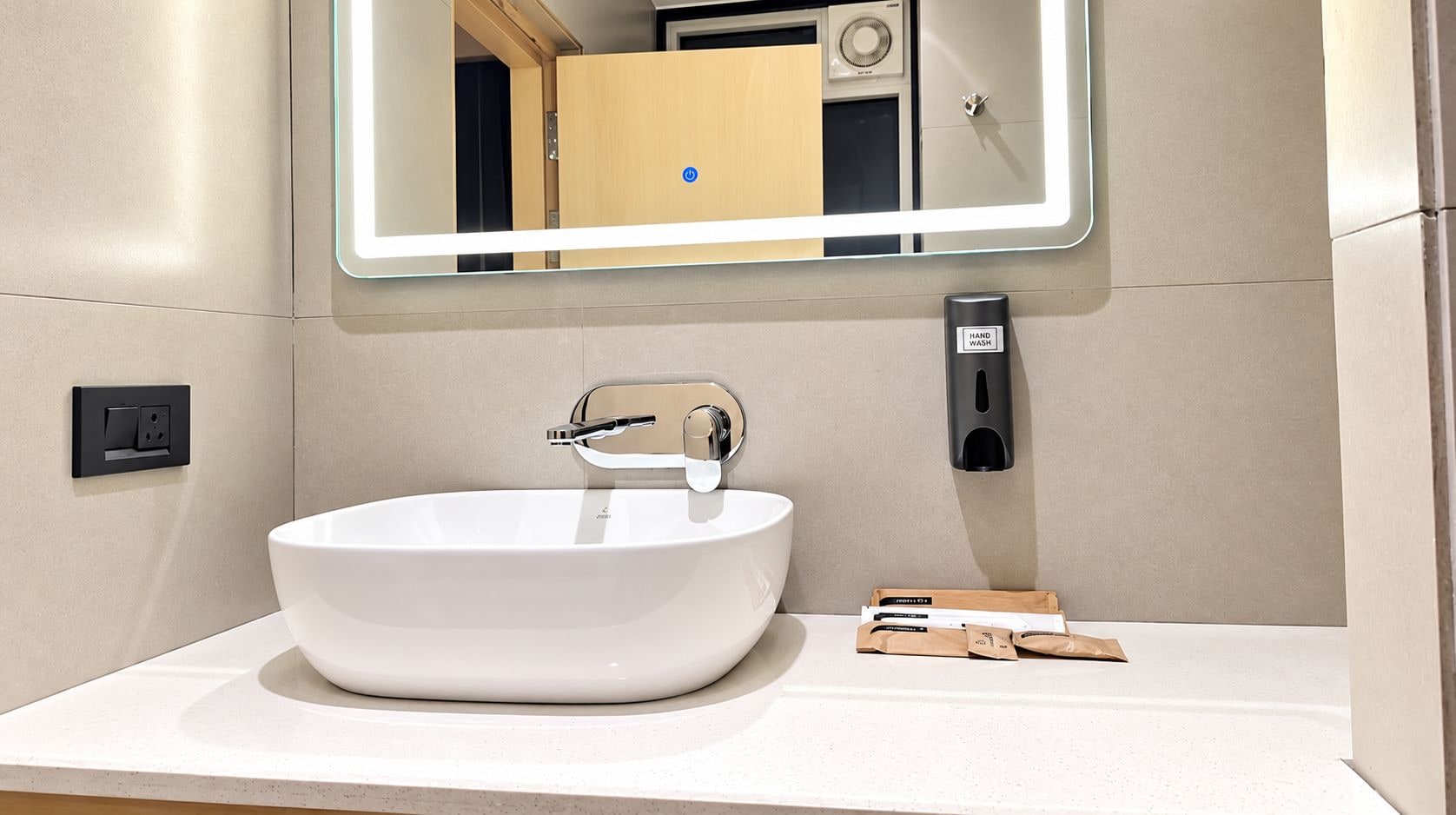 Un bagno moderno con lavandino bianco, punto lavaggio mani e specchio.