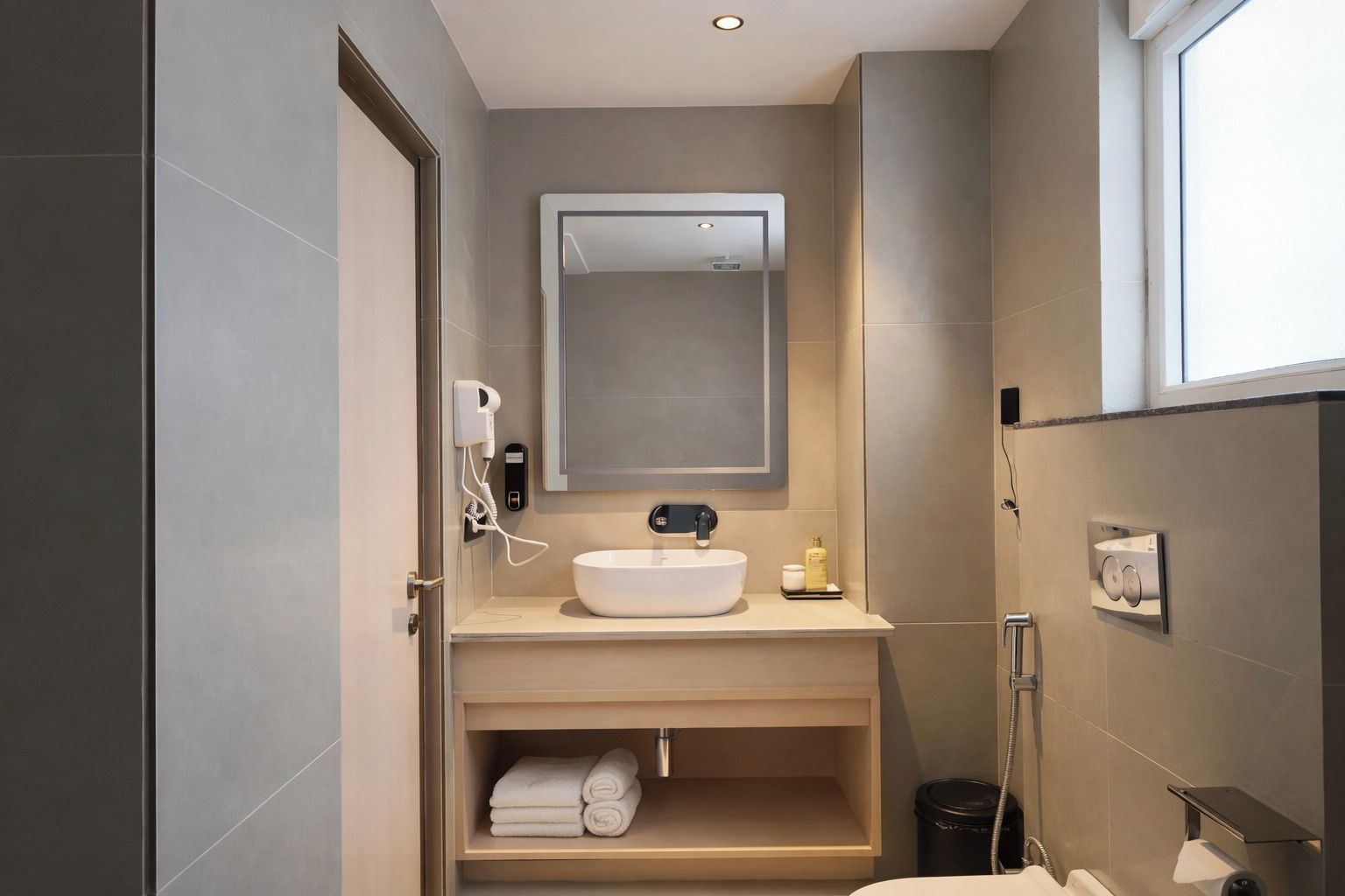 A modern bathroom with a large mirror, a sink, and a towel rack.