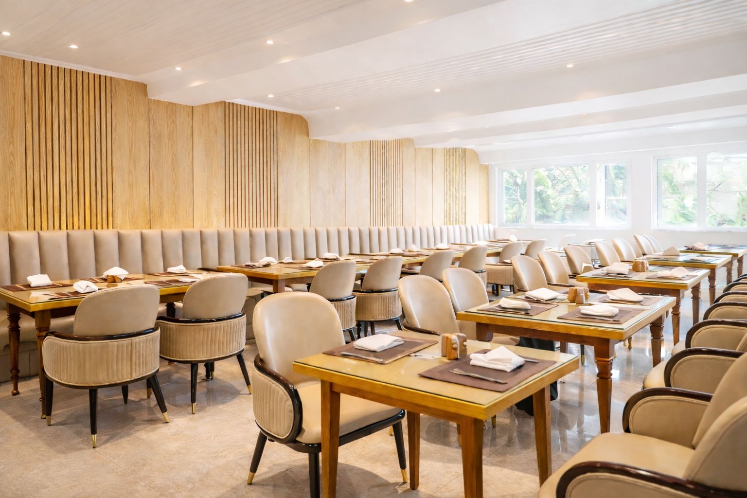 Een vergaderzaal met lange tafels en stoelen, houten paneelwanden en grote ramen.