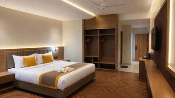 A hotel room with a large bed, a wardrobe, a television, and a ceiling fan.