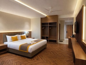 Une chambre d’hôtel équipée d’un lit, de tables de chevet, d’une armoire, d’une télévision et d’un ventilateur de plafond.