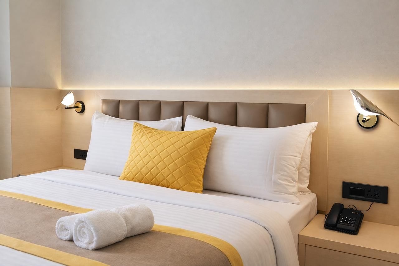 A neatly made bed with a headboard, a bedside lamp, and a telephone on a bedside table.