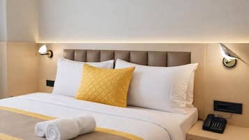 A neatly made bed with a headboard, a bedside lamp, and a telephone on a bedside table.