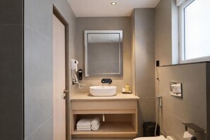 Une salle de bain moderne avec un lavabo intégré, un miroir, un porte-serviettes et un espace douche.