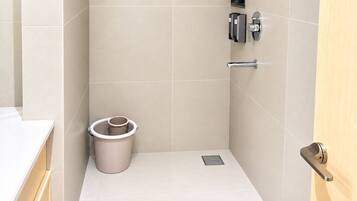 Un bagno con il water, un cestino, un asciugamano elettrico e un porta asciugamani.