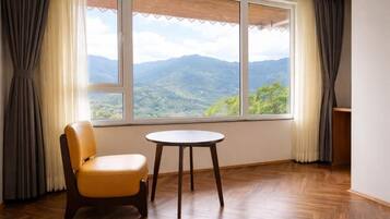 A room with a view of mountains, a chair, and a table.