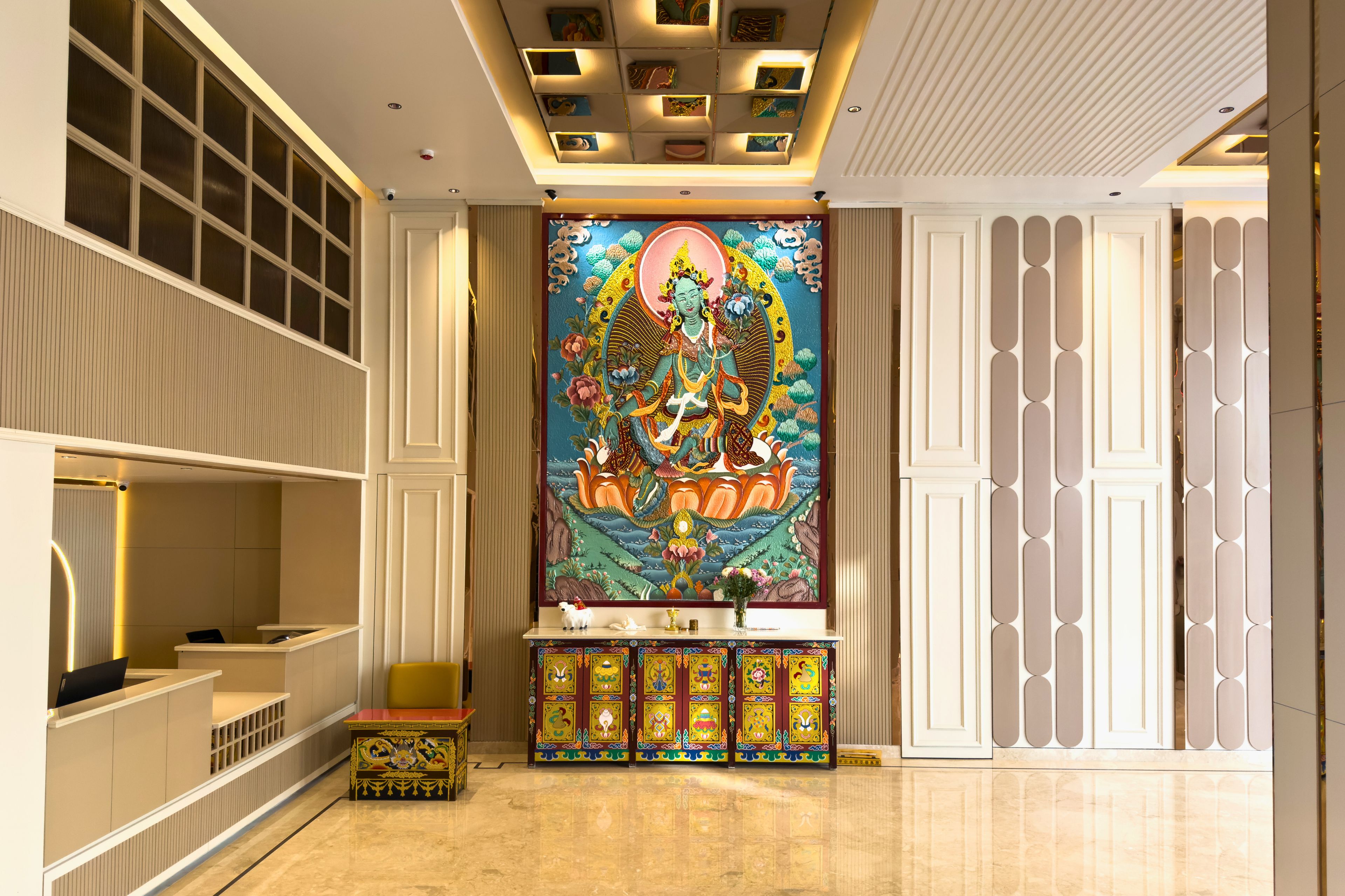 A hotel lobby with a large mural, a reception desk, and a seating area.