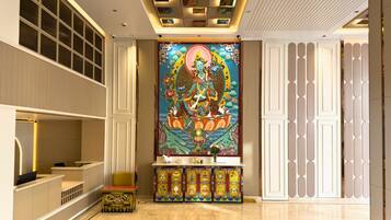 A hotel lobby with a large mural, a reception desk, and a seating area.