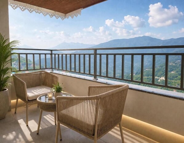 A balcony with wicker furniture, a table with a candle, and a view of mountains.