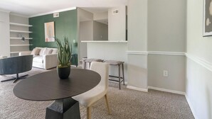 Una sala moderna con una mesa redonda, un sofá, una mesita de centro y una planta en maceta.