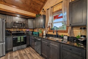 Eine moderne Küche mit Edelstahlgeräten, Holzschränken und einer Arbeitsplatte aus Granit.