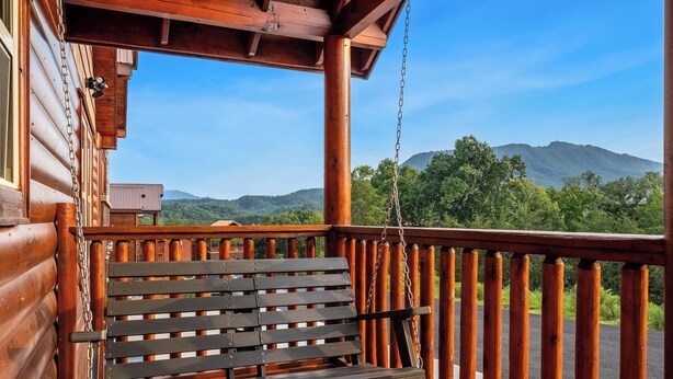 A wooden porch with a swing, overlooking a mountainous landscape. - Luxury BRAND NEW 8bdrm Cabin-Pool-Arcades-Gazebo (Sevierville)
