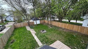 Ein Garten mit Holzzaun, Rasen und einem kleinen Schuppen.