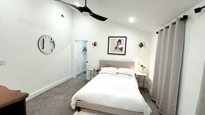 Ein Hotelzimmer mit einem Bett, einem Nachttisch, einer Lampe, einem Spiegel und einem Deckenventilator.