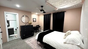 Een slaapkamer met een bed, een dressoir, een bureau, een stoel en een wereldbol op het dressoir.