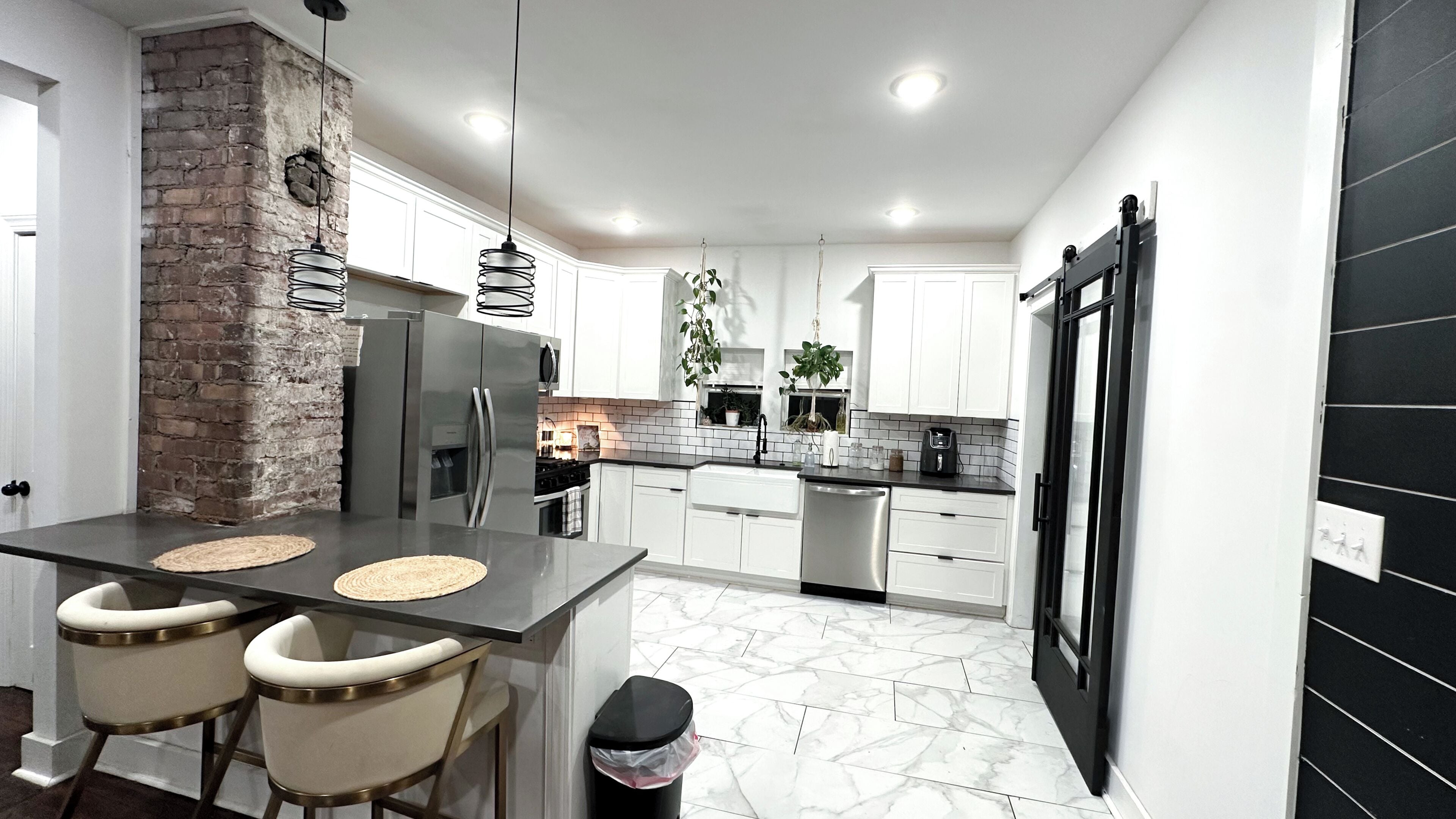A modern kitchen with a central island, white cabinetry, and a black refrigerator.