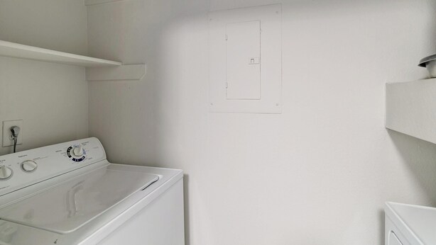 A laundry room with a front-loading washing machine, a wall-mounted drying rack, and a door with a small window. - Landing | Stylish 2BD, Gym, Clubhouse (Houston)