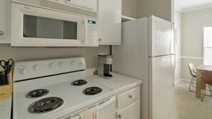 A kitchen with a microwave, stove, and refrigerator. - Landing | Stunning 1BD, Clubhouse, Gym (Houston)